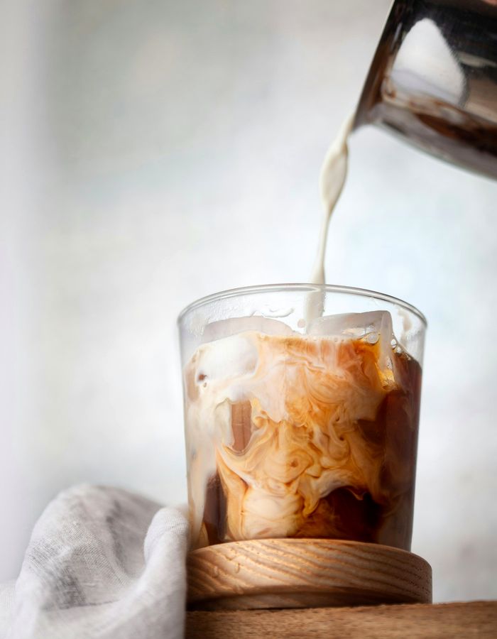 Leche cayendo sobre un vaso de cold brew con hielo
