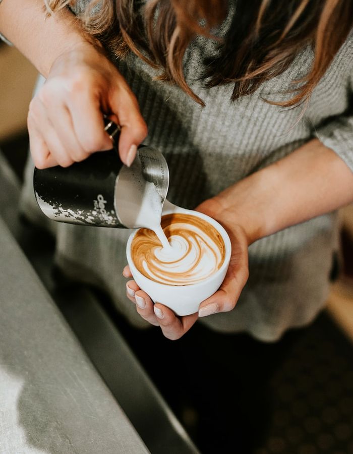 Barista sujetando una taza de flat white con latte art